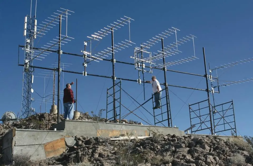 Local technicians maintaining translator equipment on a tower
